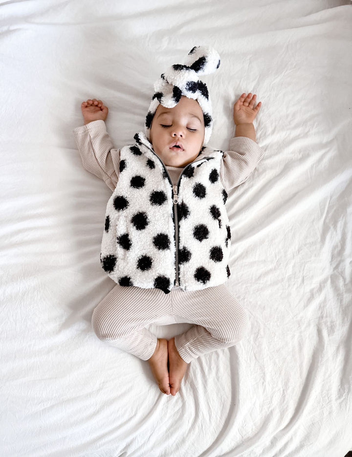 Sleeping baby wearing Bobby G waffle cotton leggings and long sleeved boxy tee in neutral colour-way with a teddy cotton vest in white and black with matching headband 