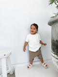 Toddler wearing white organic ribbed tee and khaki organic harem shorts 