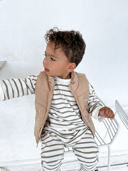 Child wearing a green and white oversized organic cotton jumper and drop crotch harem pants with brown Winter vest that has Bobby G logo printed in white on the front. 